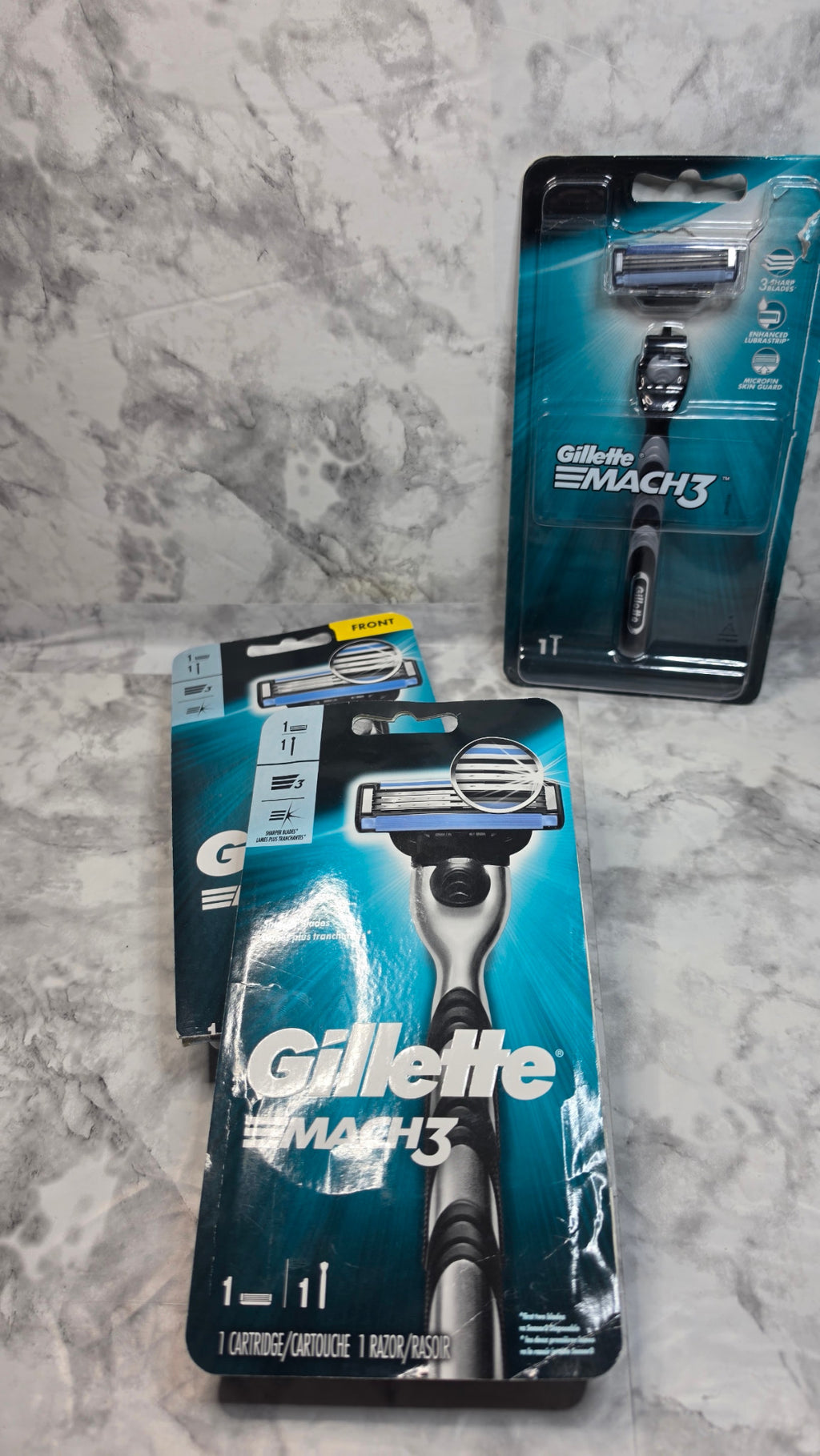 Gillette Mach3 retail packages showing creases and wear on a marble-pattern surface