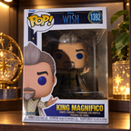 Funko Pop! King Magnifico #1392 in its original Disney Wish box on a shelf in a softly lit collector display cabinet