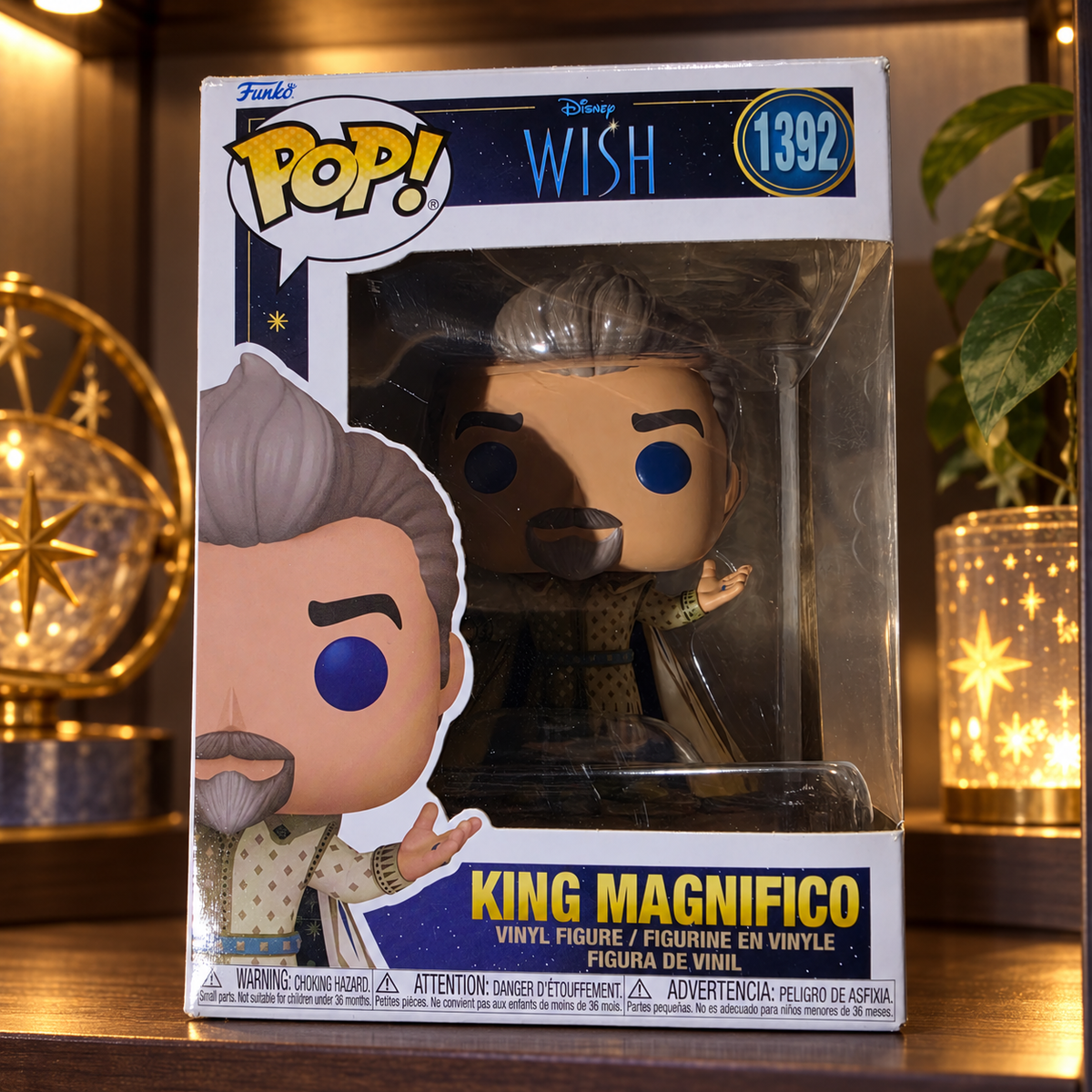 Funko Pop! King Magnifico #1392 in its original Disney Wish box on a shelf in a softly lit collector display cabinet