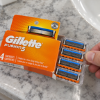 A four-cartridge tray of new-design Gillette Fusion5 refills being removed from its orange retail carton.