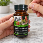 Hands removing the clear neck wrapping from a Gaia Herbs Quick Defense 20-count bottle.