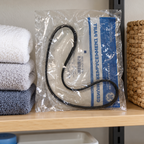 GE WH01X27538 drive belt in its labeled polybag, linen shelf lifestyle illustration