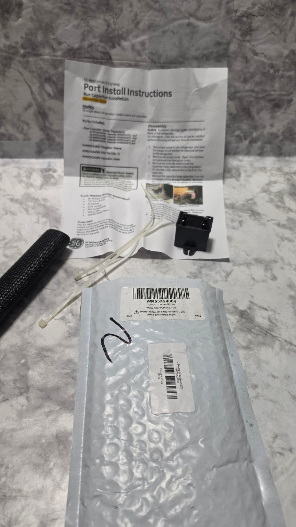 Actual GE WR55X24064 capacitor kit with sleeve, two ties, instructions and original package