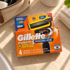 AI-generated lifestyle view of one orange Gillette Fusion5 ProGlide Shield 4-count pack beside travel toiletries; props not included