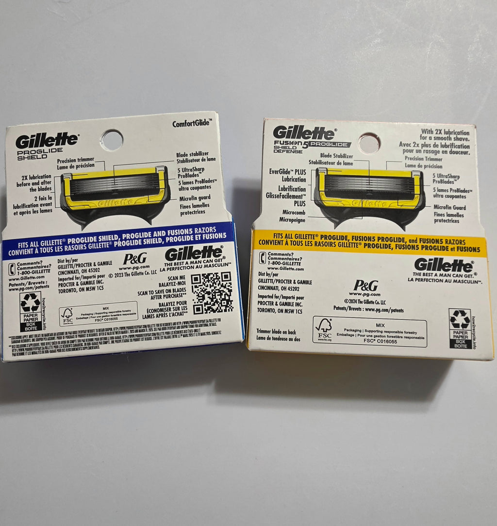 Actual backs of blue and orange Gillette Shield 4-count packaging showing five blades, precision trimmer and handle compatibility