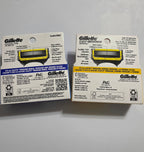Actual backs of blue and orange Gillette Shield 4-count packaging showing five blades, precision trimmer and handle compatibility