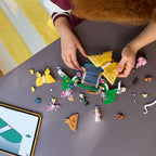 Child assembling LEGO Wicked Glinda’s Wedding Day 75688 with butterfly elements, pieces and a tablet showing building instructions.
