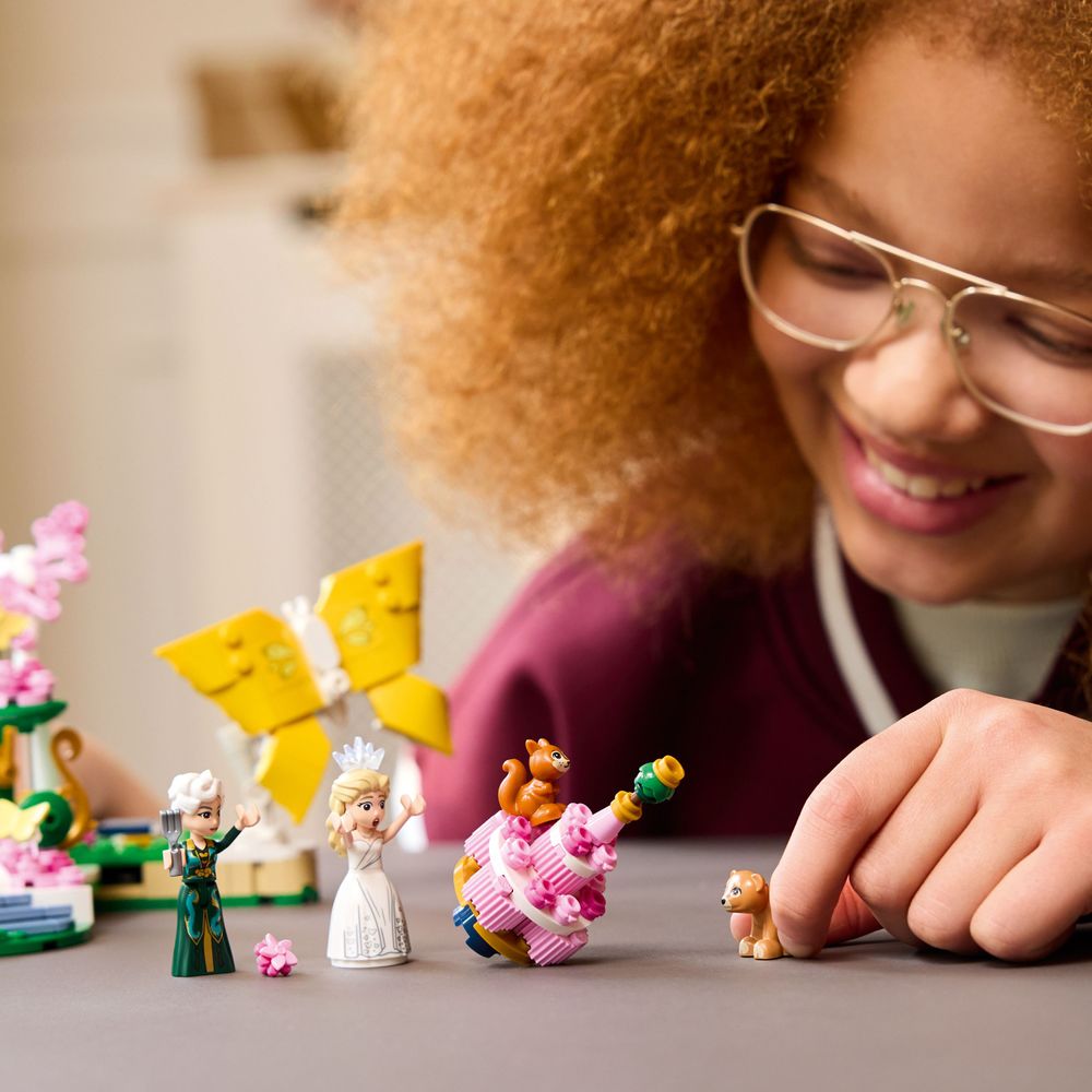 Child playing with the Glinda and Madame Morrible minidolls, wedding cake, bear cub and squirrel from LEGO Wicked 75688.