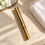 GrandeLASH-MD gold serum tube on a stone vanity beside a white washcloth