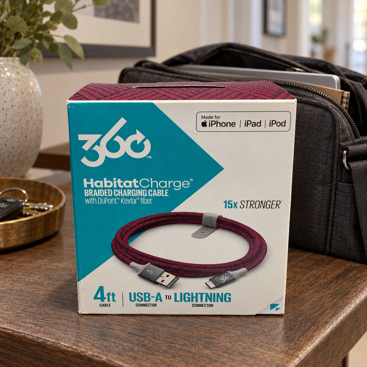 AI-generated lifestyle illustration of one closed HabitatCharge cranberry 4 ft USB-A to Lightning cable box in a work bag setting; background props not included.