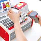 Close-up of the Hape E3184 scanner held beside a toy egg carton, with the calculator and cash drawer visible.