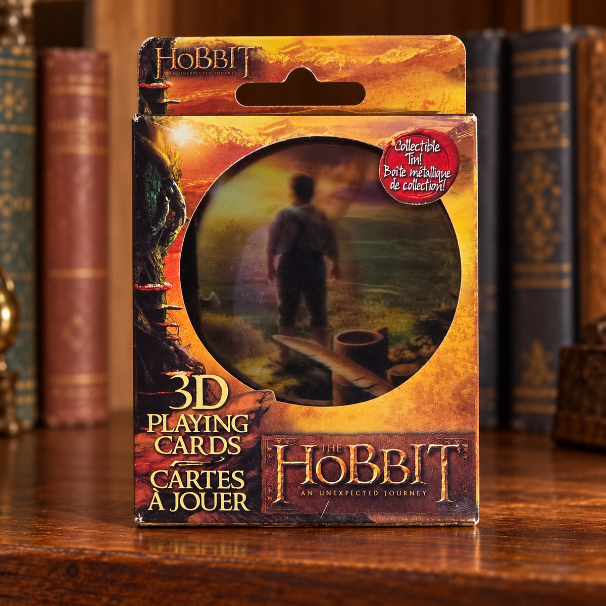 AI-generated lifestyle scene of one closed Hobbit Cartamundi 3D playing-card collectible tin retail package on a collector shelf. Props not included.