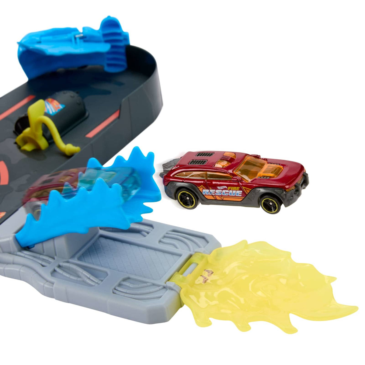 The red Hot Wheels rescue vehicle jumping past the blue wave ramp and yellow flame target on the JHL95 fire station.