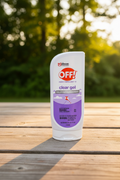 OFF! Clear Gel insect repellent bottle on wooden picnic table with green summer foliage and sunlight