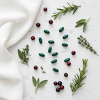Flat lay of supplement capsules with fresh green herbs and saw palmetto berries on white marble