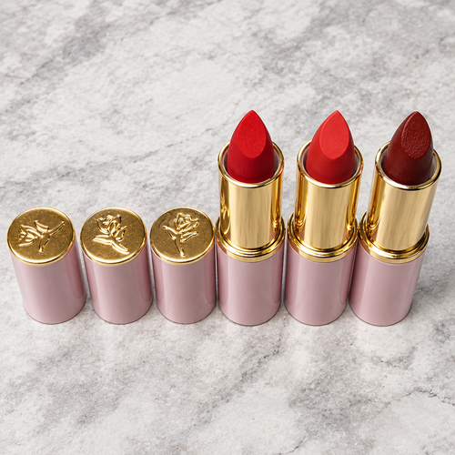 Close view of three Mary Kay Lasting Color lipstick shades with matching caps on stone