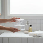 ResMed HumidAir clear water chamber being handled on white-tiled bathroom counter with high-end amenities
