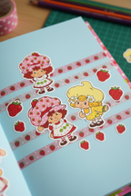 Strawberry Shortcake scratch and sniff stickers applied to scrapbook page alongside pink washi tape in colorful kids craft project