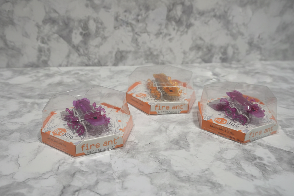 HEXBUG Fire Ant Purple, Orange, and Red variants in original hexagonal packaging on marble surface