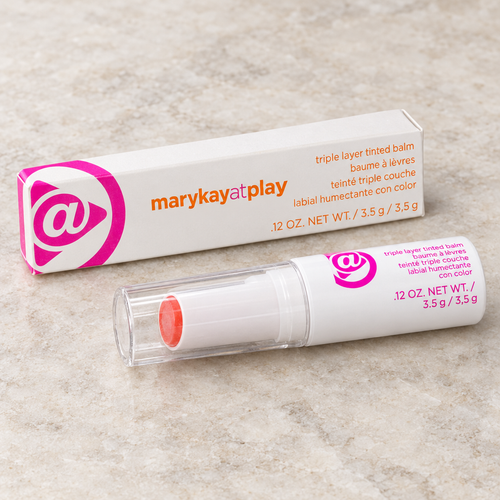 Mary Kay at Play Triple Layer Tinted Balm tube and box on a pale stone surface