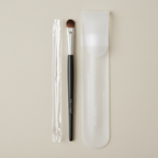 Mary Kay Eye Smudger Brush with clear sleeve and frosted storage pouch in a flat lay