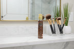 SOL by Jergens body bronzer bottle on marble bathroom vanity shelf beside cosmetic brushes