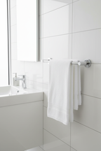 Grohe Essentials polished chrome 2-arm swivel towel bar with white fluffy towels mounted next to modern bathroom sink