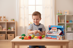 Child playing cashier with Hape Beep n Buy Wooden Cash Register scanning play food in bright playroom - More4less Outlet