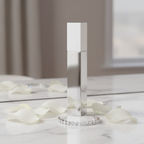 Lifestyle image — slim white and silver perfume wand box on white marble vanity beside diamond bracelet and white rose petals, sparkling elegant editorial for visual context only