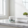 Olay Sensitive Eczema Therapy Skin Relief Cream jar on marble bathroom countertop with white towel and green plant – fragrance-free skincare setting
