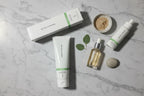 Flat lay of Rodan + Fields SOOTHE Calming Gel Cleanser tube and box alongside neutral skincare palette on marble