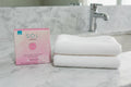 SOL by Jergens pink tanning towelettes box on marble bathroom counter beside white face towel