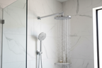 Grohe Rainshower polished chrome wall mount shower arm on white marble tile with wide rain shower head and water cascading