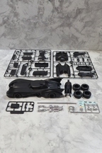AMT 1989 Batman Batmobile model kit parts flat lay showing black plastic sprues vinyl tires metal axle chrome parts and resin Batman figure before assembly
