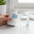 Hand holding Thorne Zinc Picolinate 30 mg bottle beside glass of water on marble countertop in morning wellness routine