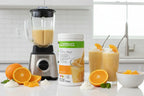 Smoothie station setup on minimalist counter with fresh citrus garnish alongside Herbalife Formula 1 Orange Cream canister