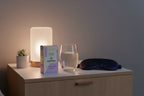 Winged Wellness Sleepyhead gummies box on nightstand with glass of water and silk sleep mask