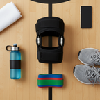 Flat lay of hinged knee brace with water bottle, athletic shoes, and resistance bands on wooden gym floor