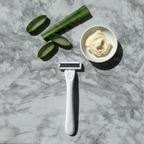 Minimalist spa flat lay with aloe vera, shea butter cream, and sleek white razor on marble