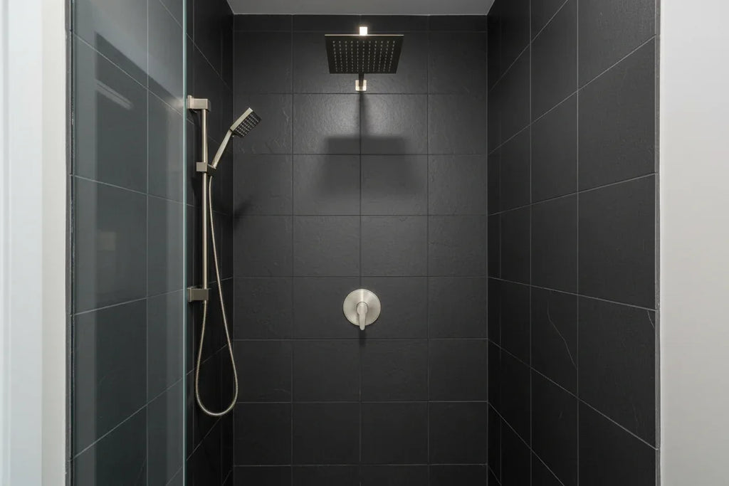 Minimalist professional shower stall featuring Pfister brushed nickel valve trim against dark slate tile