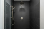 Minimalist professional shower stall featuring Pfister brushed nickel valve trim against dark slate tile