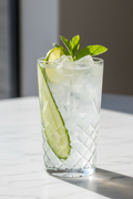 Tall gin and tonic with cucumber slice and ice in a Riedel Spey cut-crystal longdrink highball glass on marble surface