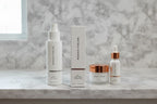 Morning skincare setup with Rodan + Fields peel box and white cosmetic bottles on neutral stone surface