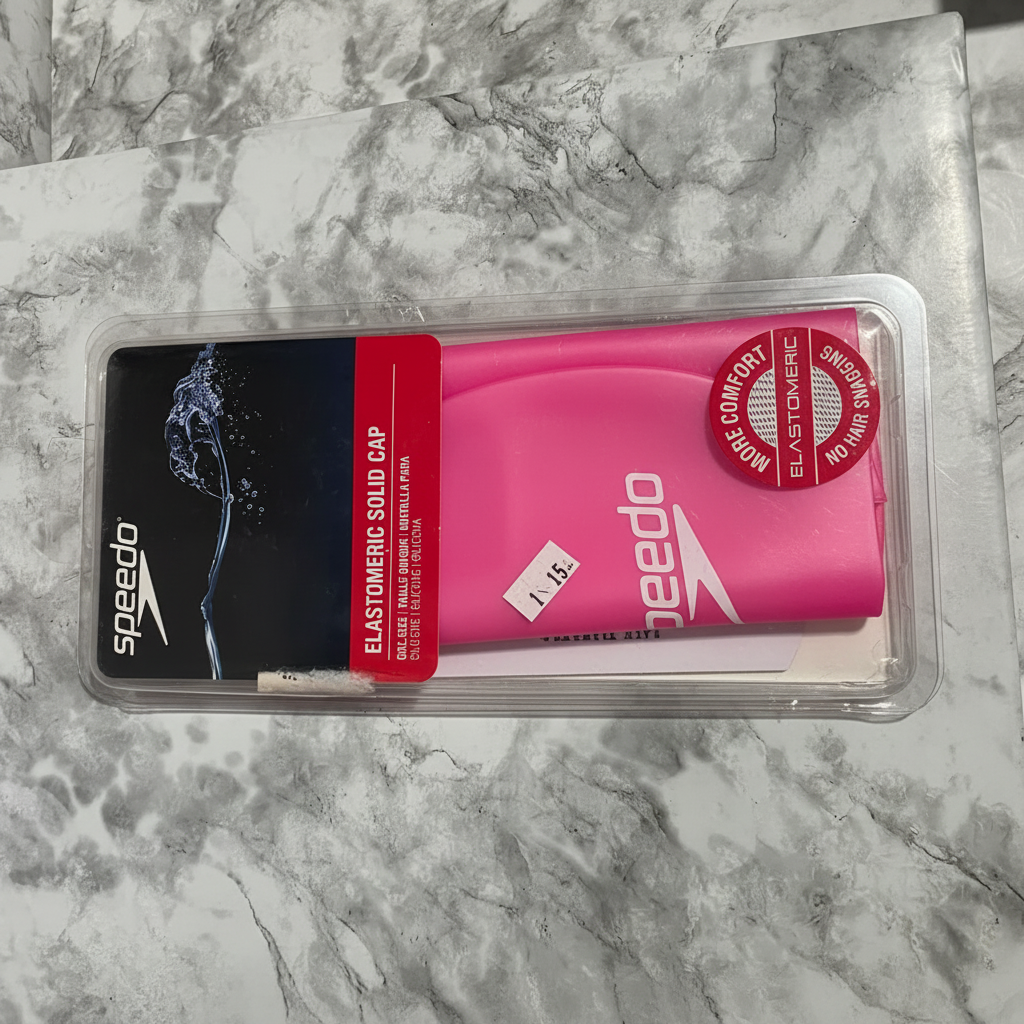 Front view of pink Speedo Elastomeric Solid Swim Cap in sealed clamshell packaging showing More Comfort Elastomeric badge