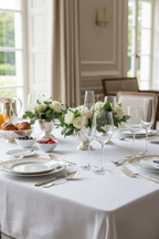 Formal dining brunch table setup with elegant Riedel white wine and champagne crystal stemware, white tablecloth and fresh flowers