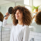 Teenage girl with defined curly hair diffusing hair with hair dryer in bright bathroom happy lifestyle photo
