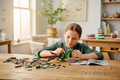 Child building LEGO Creator 31161 Medieval Dragon at a wooden table with bricks spread out