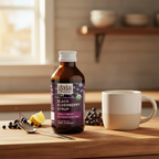 Gaia Herbs Black Elderberry Syrup bottle beside a spoon, mug, elderberries, and lemon in a warm kitchen