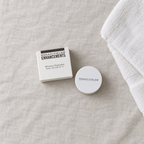 Flat lay of Rodan + Fields Mineral Peptides box and closed jar on linen beside a towel