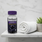 Sambucol Black Elderberry Gummies bottle on bathroom vanity shelf with rolled white organic cotton face towel and small green succulent